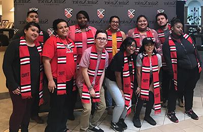 TRIO students standing in front of an SXU backdrop with their stoles